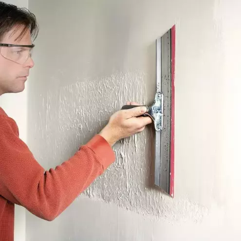 Man applying skim coat to dry wall